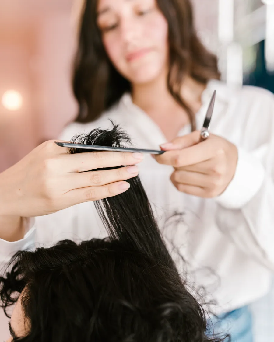Estilista realizando un corte de cabello para dama con técnica profesional
