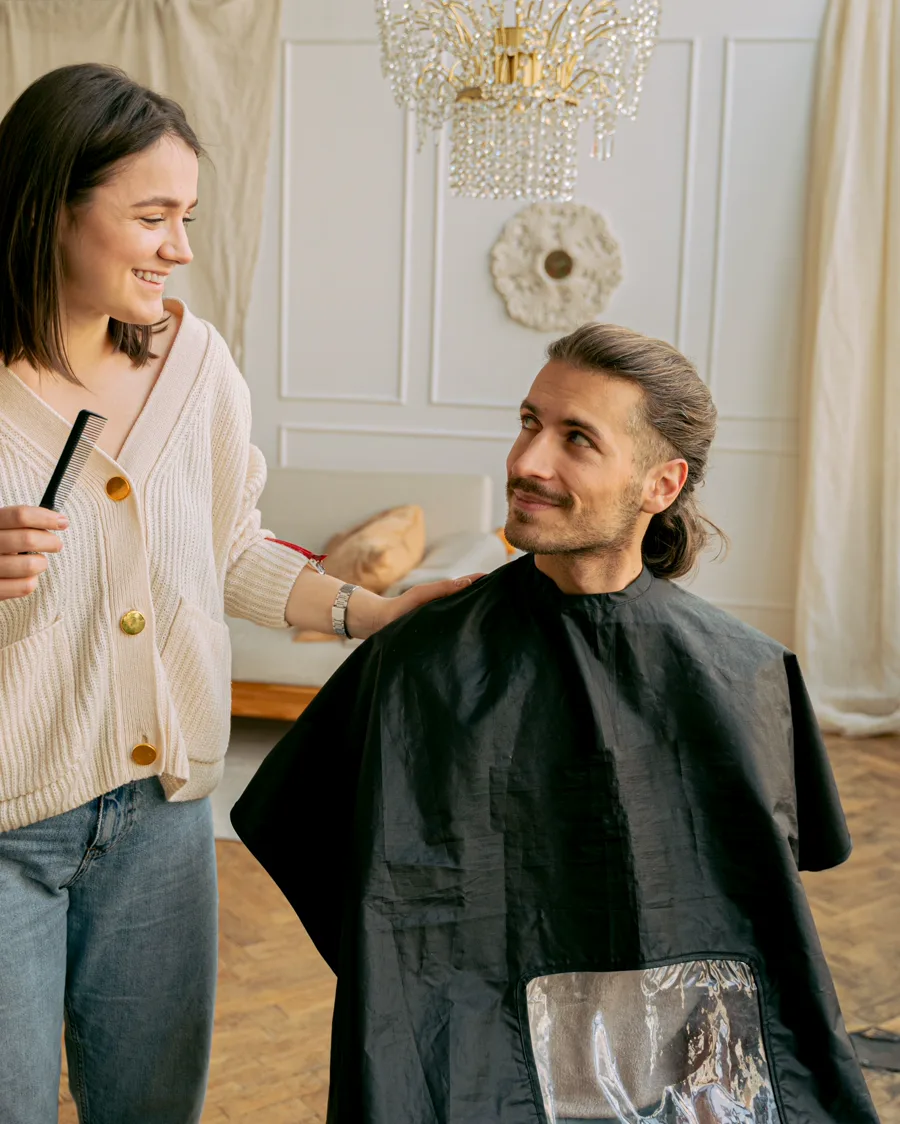 Estilista atendiendo a un hombre durante un corte de cabello profesional
